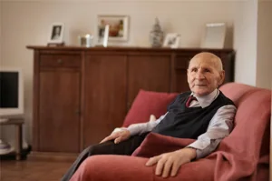 Alert1 Senior Sitting On Red Sofa Alert1 Senior Sitting On Red Sofa