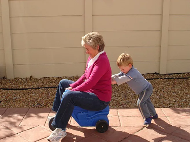 Child pushing grandma on plastic toy car. Child pushing grandma on plastic toy car.