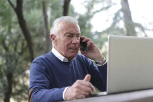 Older Man Using Laptop and Cell Phone Older Man Using Laptop and Cell Phone