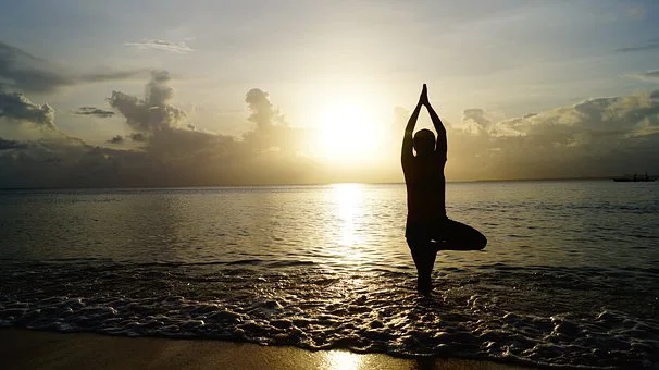 senior doing tree pose at beach
