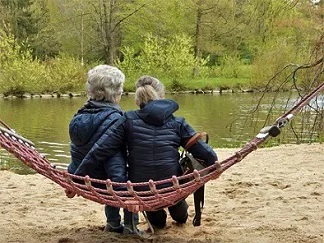 Two people sitting on a swing facing the lake Two people sitting on a swing facing the lake