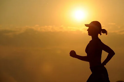 Silhouette of woman running in front of setting sun Silhouette of woman running in front of setting sun