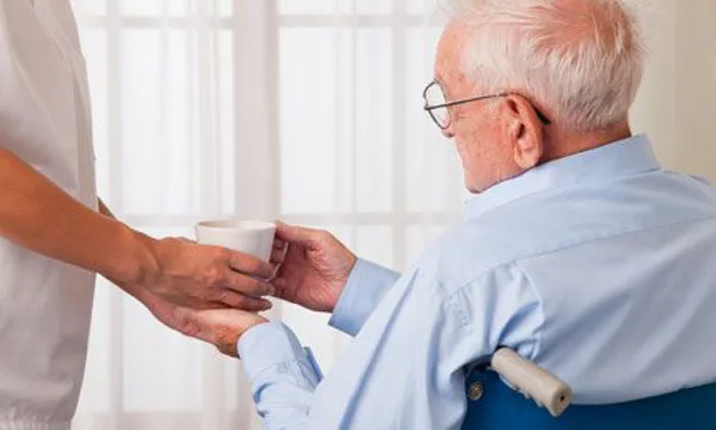man getting water from caregiver man getting water from caregiver